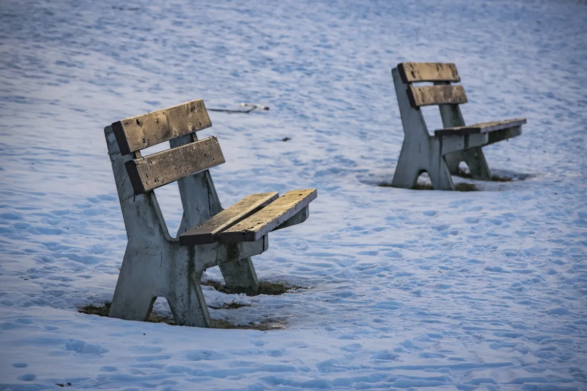 Two empty wooden chairs standing in the snow